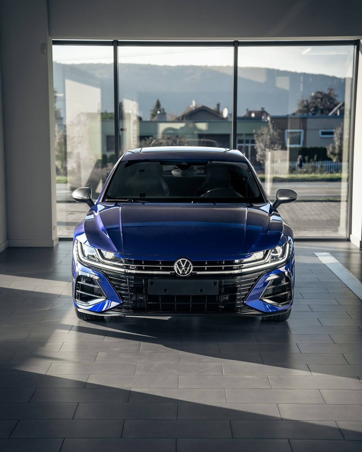 Dark blue Volkswagen sedan parked on a showroom floor.